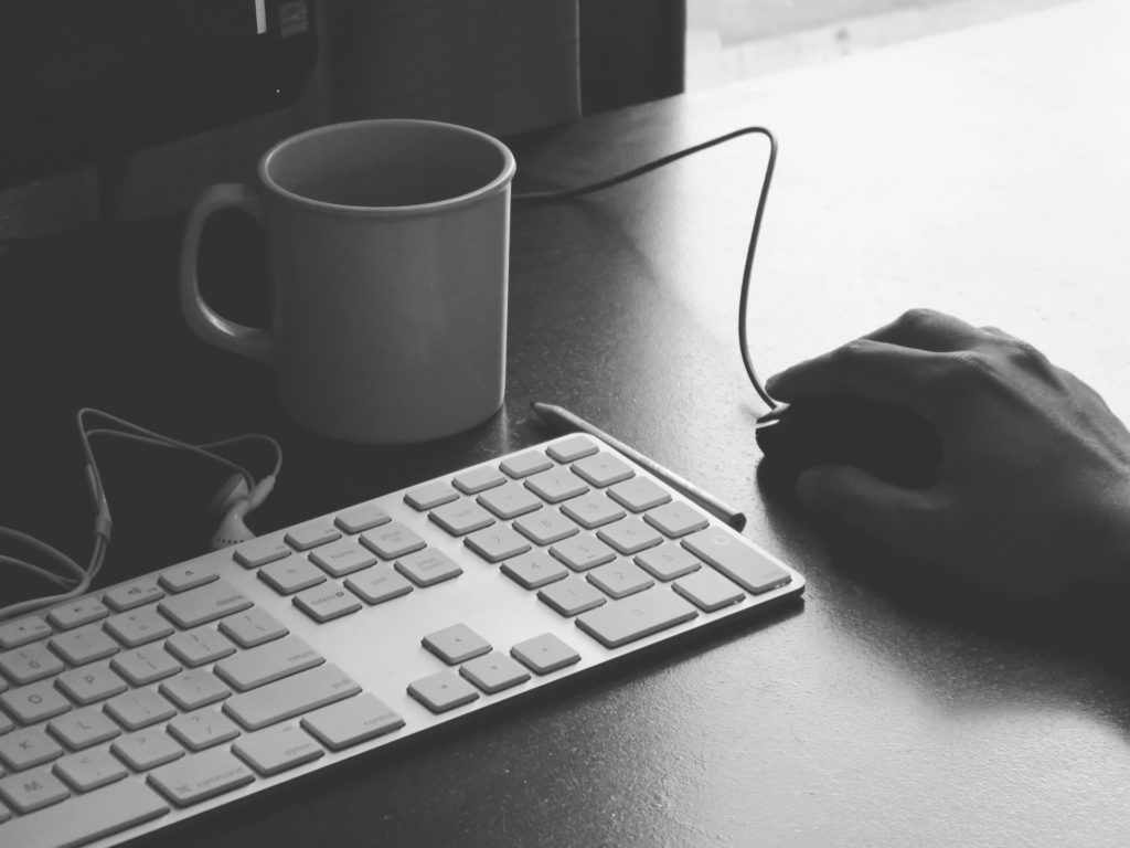 an image of hand holding mouse near computer